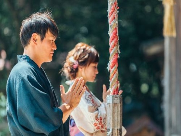 神社で縁結びを祈願する男女のイメージ
